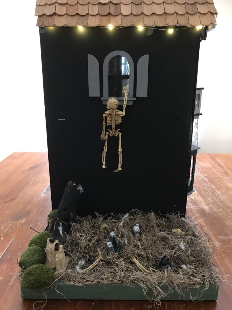 A skeleton tries to climb into this haunted dollhouse